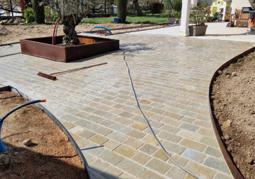 Réalisation d'une cours en pavés calcaire avec bordure et jardinière acier corten chez un particulier à la Chapelle de Guinchay